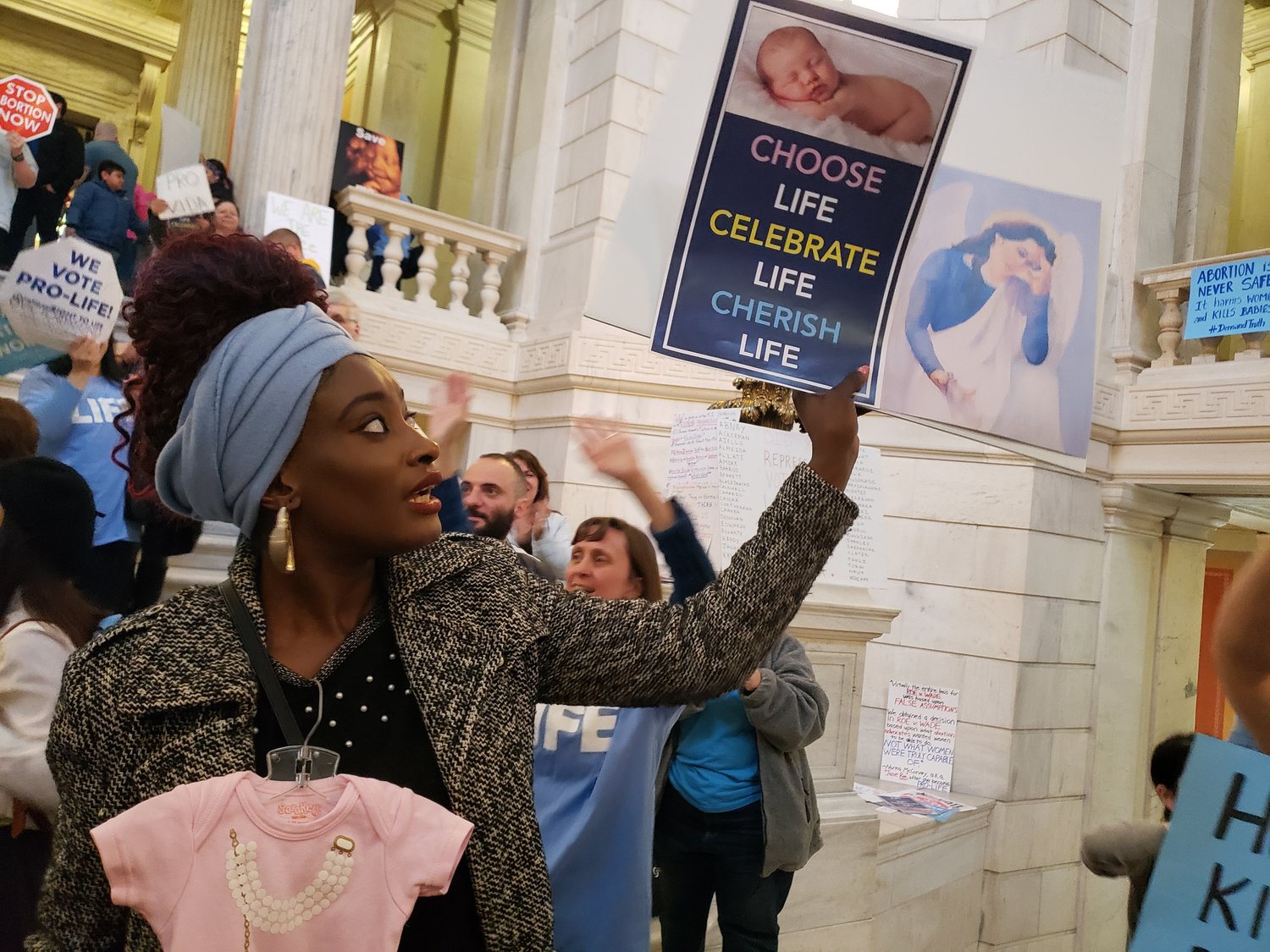 Elizabeth Koroma of Providence holds aloft pro-life signs in opposition to a Senate bill to expand legal abortion in Rhode Island.